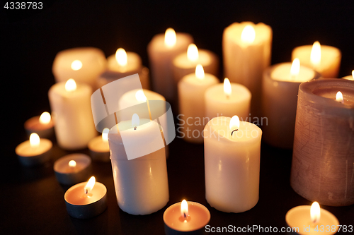 Image of candles burning in darkness over black background