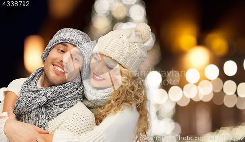 Image of happy couple hugging over christmas lights