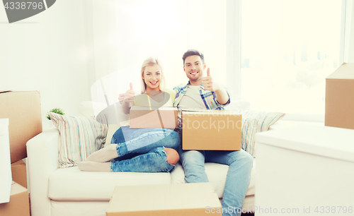 Image of happy couple with boxes showing thumbs up at home