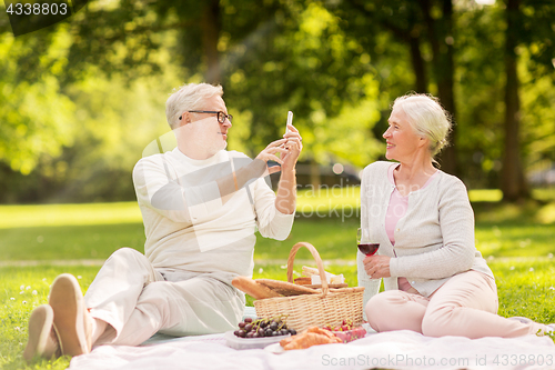 Image of senior couple taking picture by smartphone at park