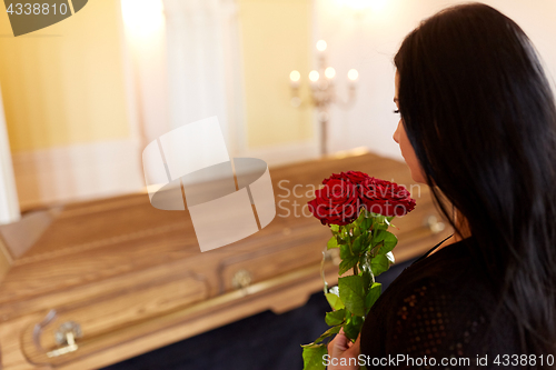 Image of woman with red roses and coffin at funeral