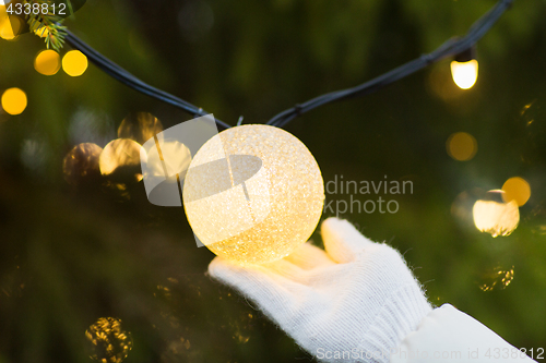 Image of close up of hand with christmas tree garland bulb