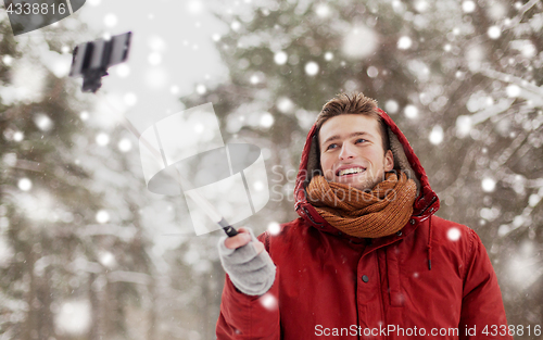 Image of happy man taking selfie by smartphone in winter