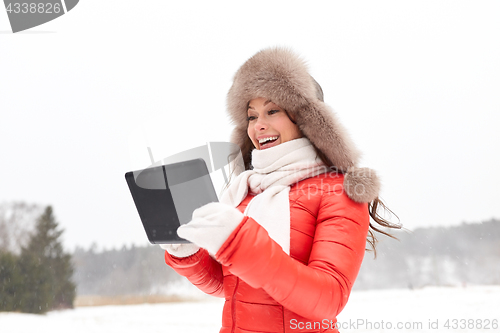 Image of woman in winter fur hat with tablet pc outdoors