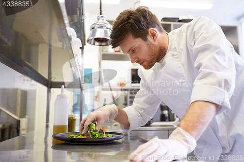 Image of happy male chef cooking food at restaurant kitchen
