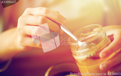 Image of close up of woman hands with honey jar and spoon