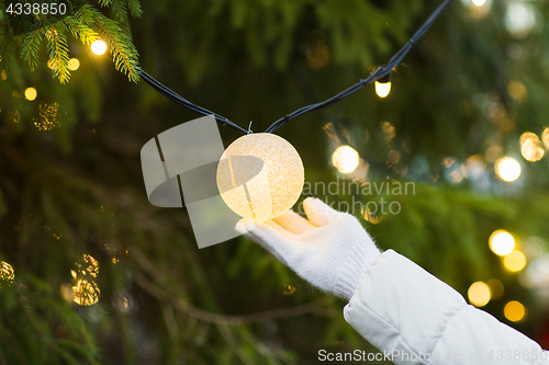 Image of close up of hand with christmas tree garland bulb