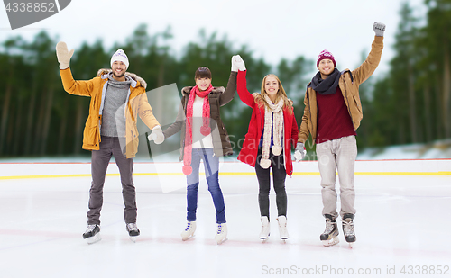 Image of happy friends waving hands on outdoor skating rink