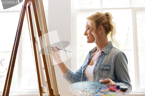 Image of woman artist with easel painting at art studio