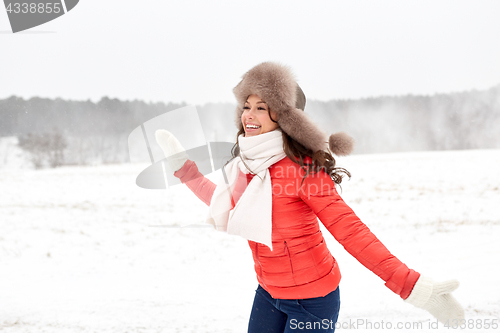 Image of happy woman in winter fur hat having fun outdoors