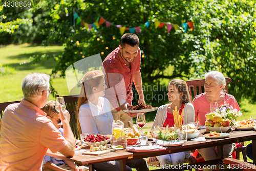 Image of happy family having dinner or summer garden party