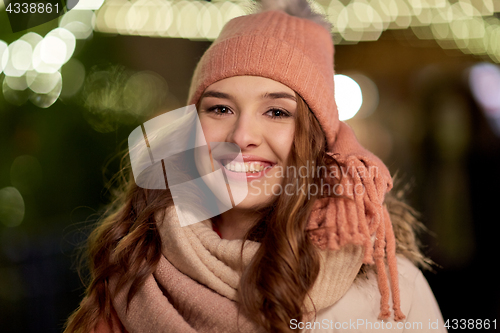 Image of happy young woman over christmas lights in winter