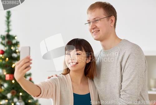 Image of mixed-raced couple taking selfie at christmas