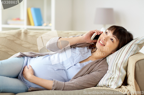 Image of happy pregnant woman calling on smartphone at home