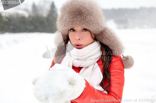 Image of happy woman with snow in winter fur hat outdoors