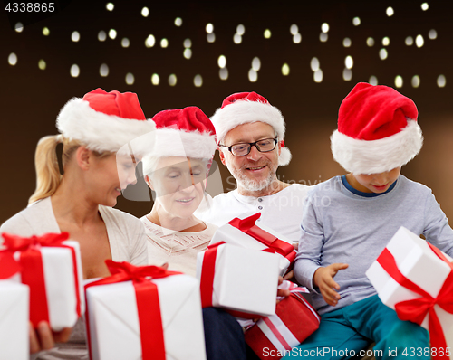 Image of happy family in santa hats with christmas gifts