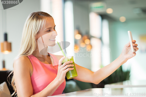 Image of woman with smartphone taking selfie at restaurant