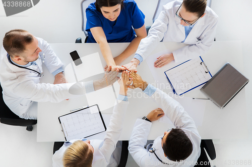 Image of group of doctors making high five at table