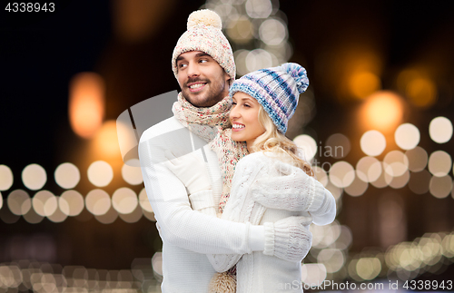 Image of happy couple hugging over christmas lights