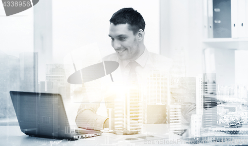 Image of smiling businessman with laptop and documents