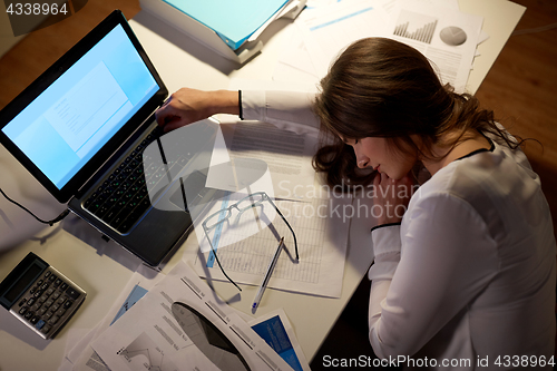 Image of tired woman sleeping on office table at night