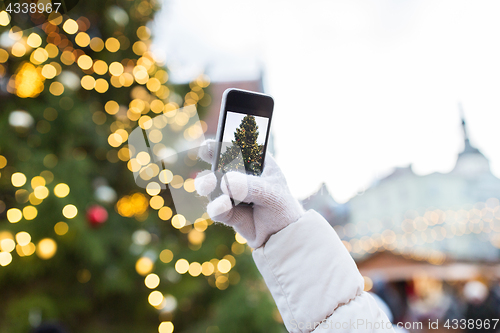 Image of hands with smartphone photographing christmas tree