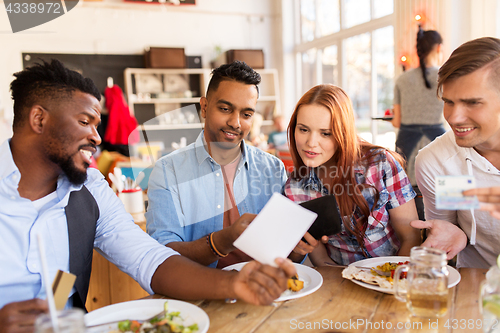 Image of happy friends with money paying bill at restaurant