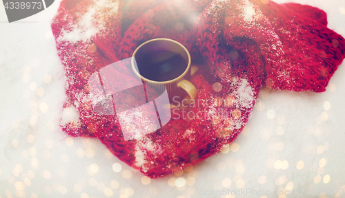 Image of tea or coffee mug and winter scarf on snow