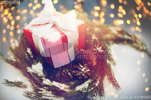 Image of christmas gift and fir wreath with cones on snow