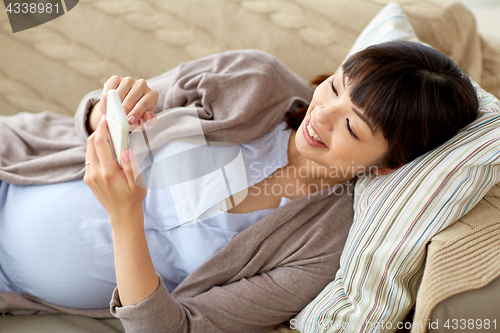 Image of happy pregnant woman with smartphone at home