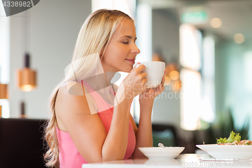 Image of woman eating and drinking coffee at restaurant