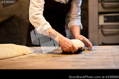 Image of baker portioning dough with bench cutter at bakery