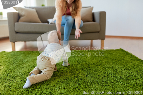 Image of happy young mother playing with baby at home