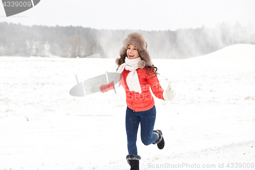 Image of happy woman in winter fur hat having fun outdoors