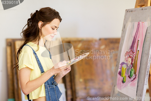 Image of student girl with easel painting at art school