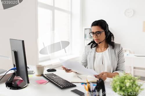 Image of businesswoman with headset and papers at office