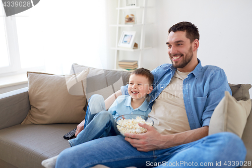 Image of father and son with popcorn watching tv at home