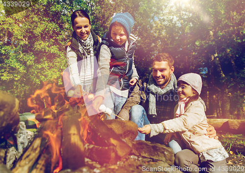 Image of happy family roasting marshmallow over campfire