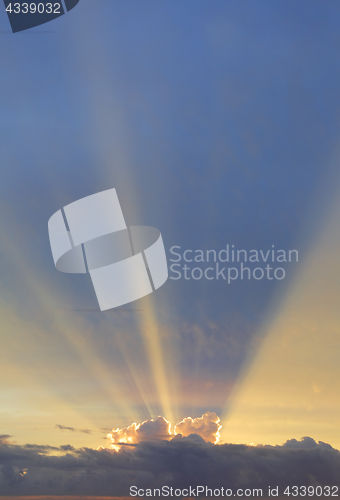 Image of Vertical sky with sun rays bursting forth from behind clouds edg