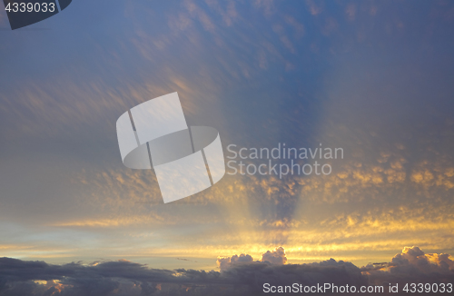 Image of Golden sun rays from behind clouds stretch across the sky above