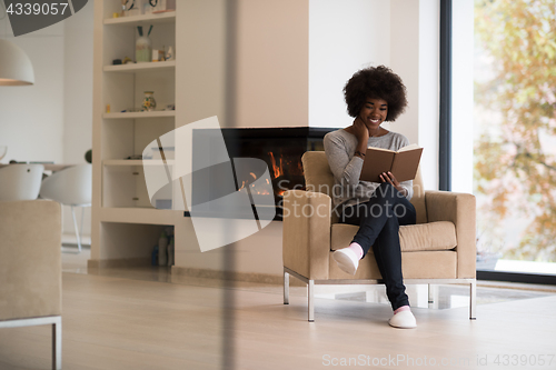 Image of black woman at home reading book