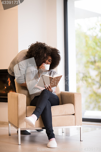 Image of multiethnic couple hugging in front of fireplace