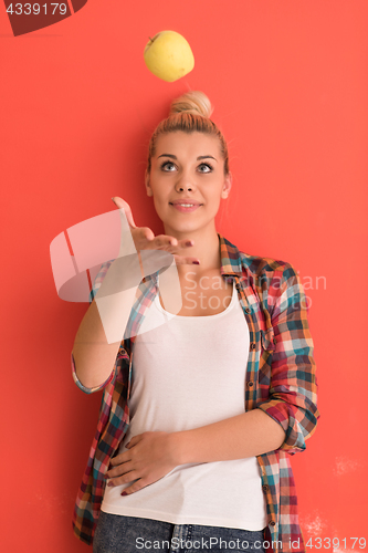 Image of woman over color background plays with apple