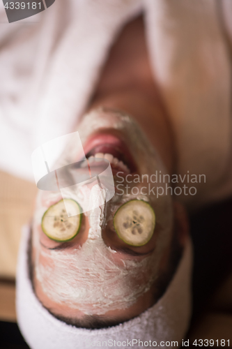 Image of woman is getting facial clay mask at spa