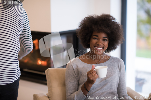 Image of black woman reading book  in front of fireplace