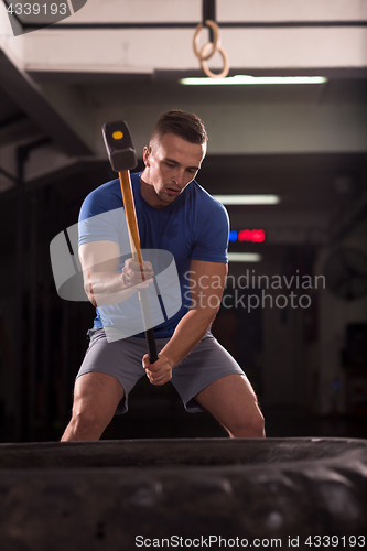 Image of man workout with hammer and tractor tire