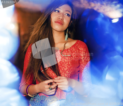 Image of young pretty asian girl in bright colored interior on carpet