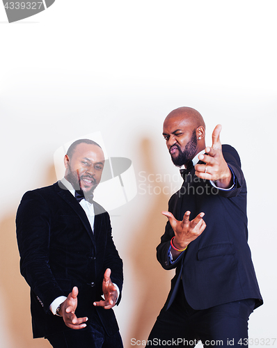 Image of two afro-american businessmen in black suits emotional posing, gesturing, smiling. wearing bow-ties 