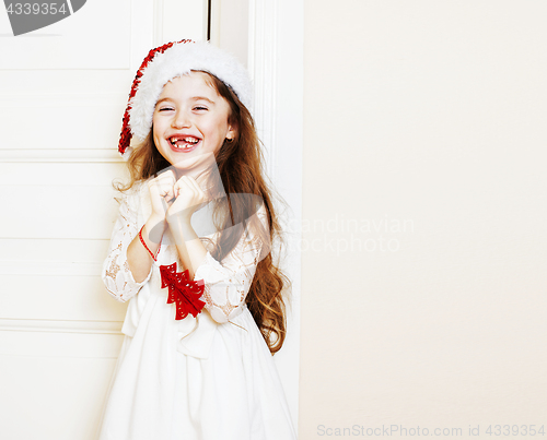 Image of little cute girl in santas red hat waiting for Christmas gifts. 
