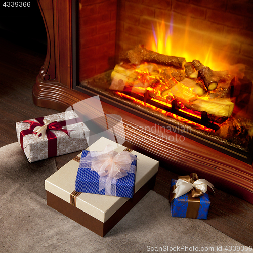 Image of Christmas gifts boxes near fireplace